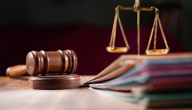 Focus on hammer, group of case files on judge’s table.