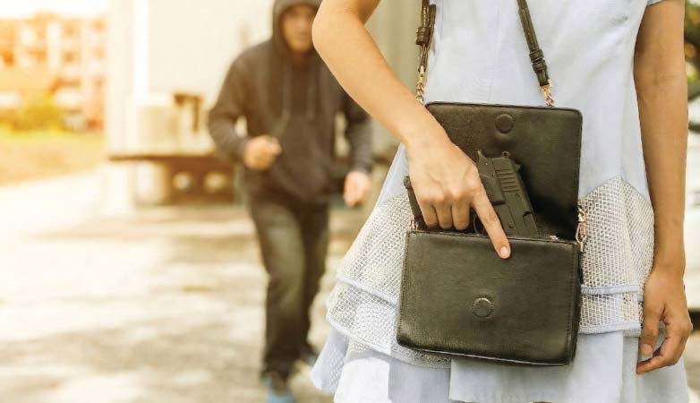 Young Woman pulls a gun from her bag while a criminal follows her.