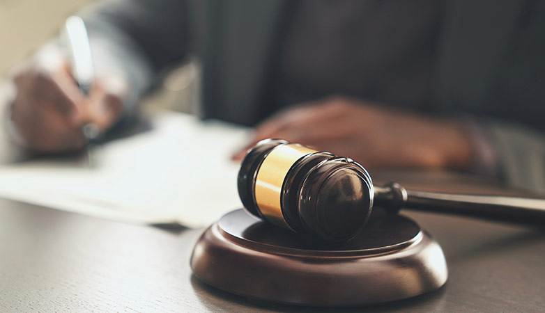 A document being signed by a judge, with a gavel next to them.