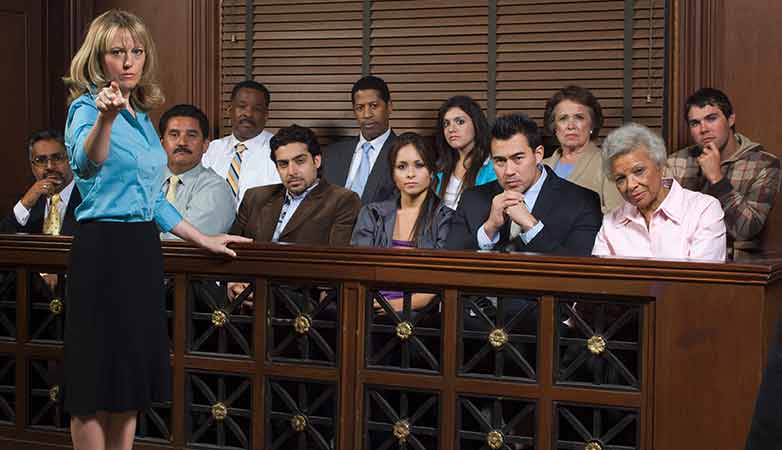 Female prosecutor standing by jury box in court.